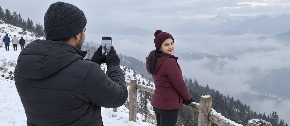Nav photographing Vandana at a snowy railing in Auli, with cloud filling the valley below